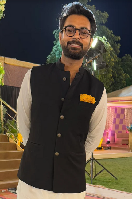 Man in formal attire standing in an outdoor decorated area at night